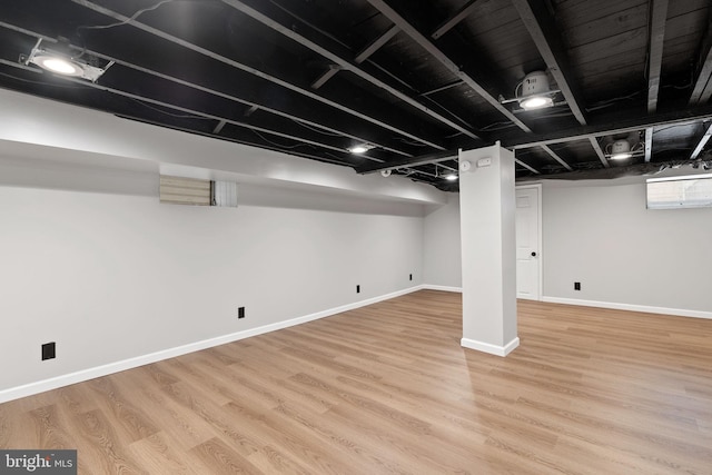 finished below grade area with light wood-style flooring and baseboards