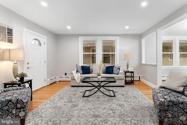 living room with a baseboard heating unit, baseboards, light wood-style flooring, and recessed lighting