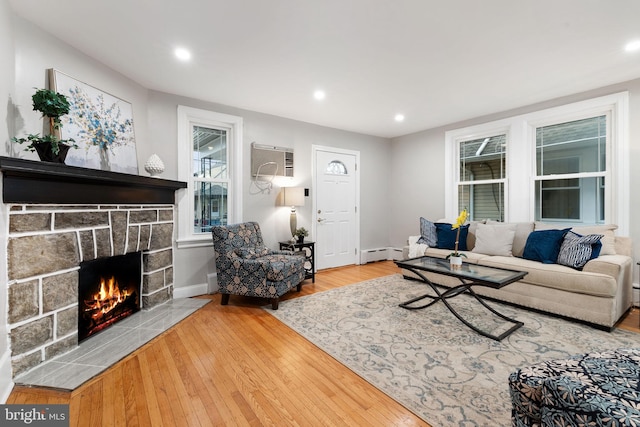 living room featuring wood-type flooring, baseboard heating, a wall mounted AC, a fireplace, and recessed lighting