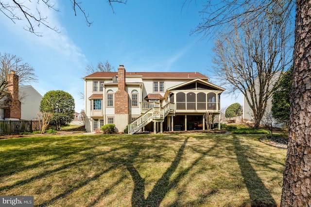 back of property featuring a yard, a chimney, stairway, a sunroom, and fence