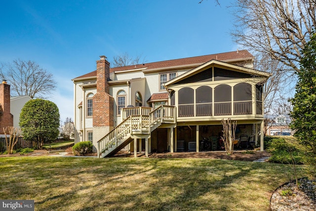 back of property with a sunroom, a chimney, stairway, and a lawn