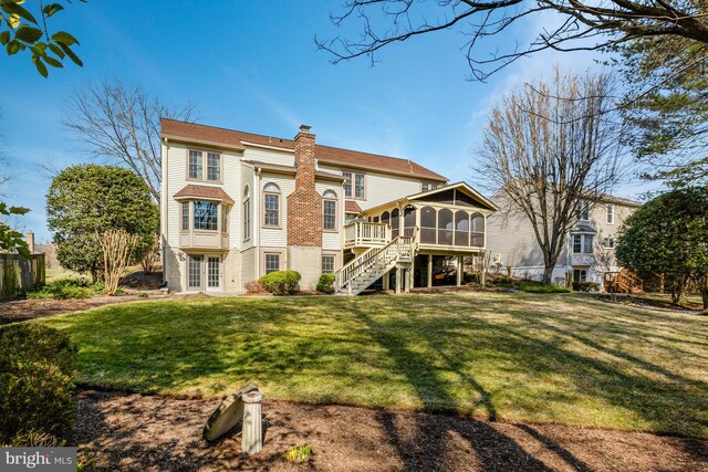 rear view of property with a lawn, a sunroom, a chimney, stairway, and fence