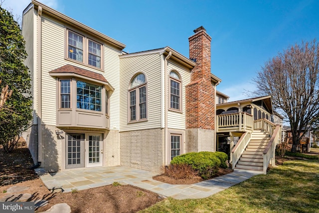 exterior space featuring a lawn, a chimney, stairway, a patio area, and brick siding