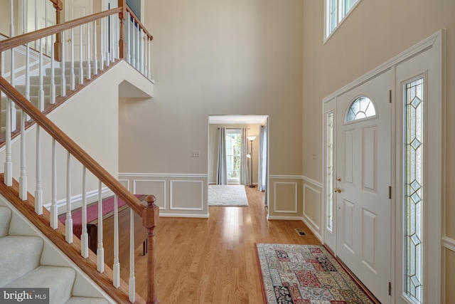 entryway featuring a wainscoted wall, a decorative wall, stairway, and wood finished floors