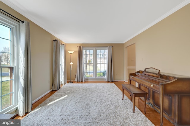 living area featuring ornamental molding, light wood-style flooring, and baseboards