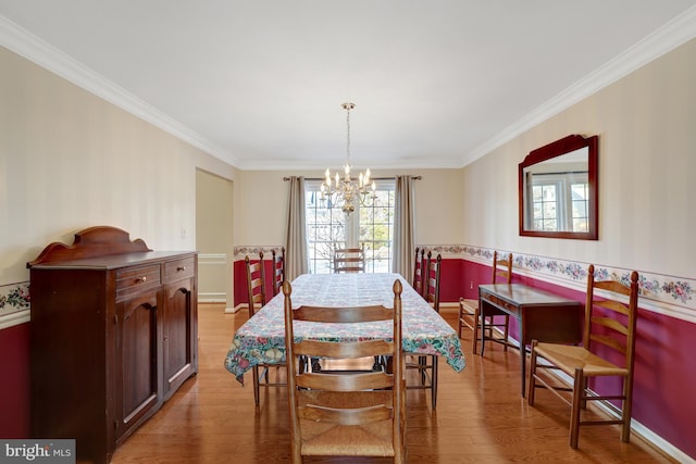 dining area featuring light wood finished floors, ornamental molding, and an inviting chandelier