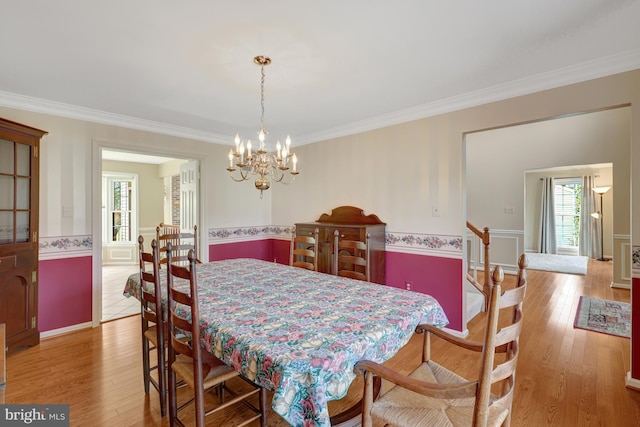 dining space featuring wainscoting, crown molding, a notable chandelier, and hardwood / wood-style floors