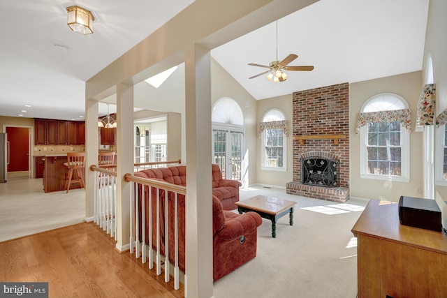 living area with light wood-style flooring, a fireplace, and vaulted ceiling