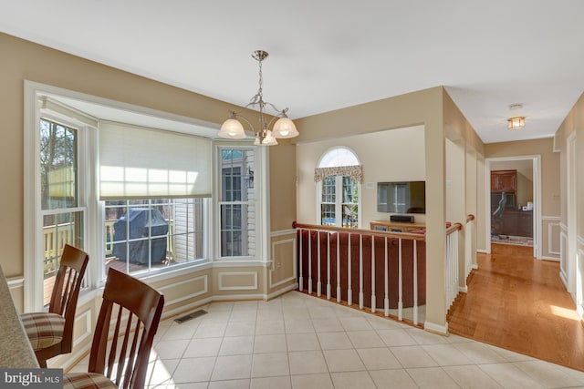 dining room featuring visible vents, a decorative wall, a notable chandelier, and light tile patterned floors