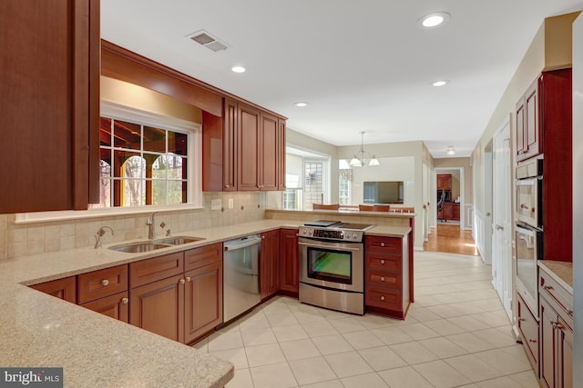 kitchen with visible vents, backsplash, appliances with stainless steel finishes, a sink, and a peninsula