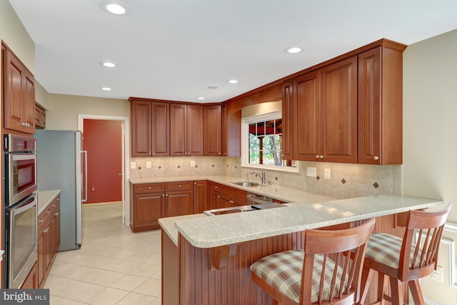 kitchen featuring stainless steel appliances, a sink, a peninsula, and a breakfast bar area