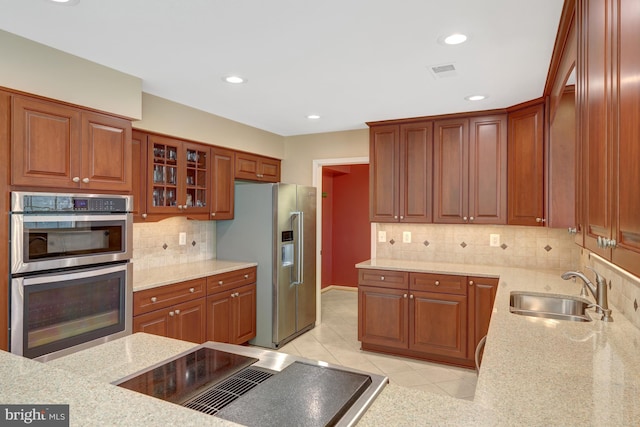 kitchen featuring appliances with stainless steel finishes, visible vents, a sink, and light stone counters