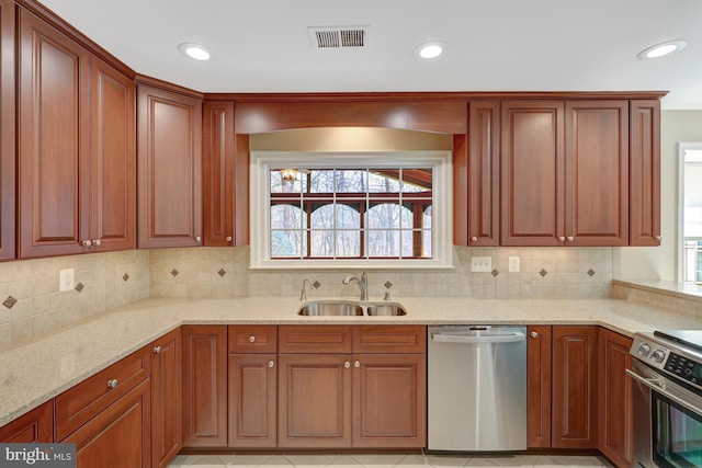 kitchen with light stone countertops, stainless steel appliances, a sink, visible vents, and decorative backsplash