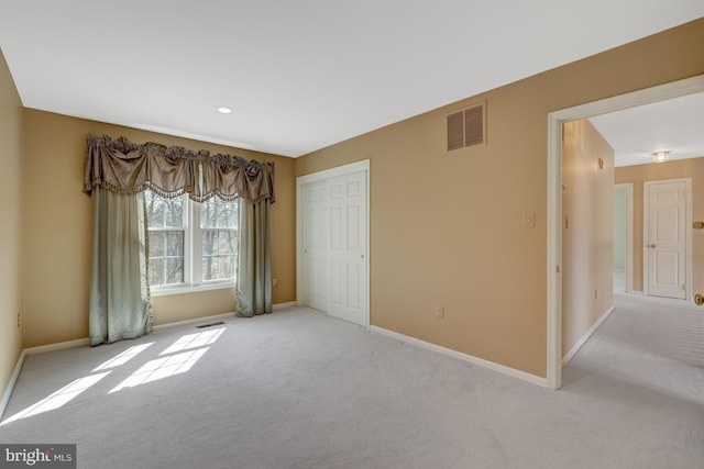 spare room with light colored carpet, visible vents, and baseboards