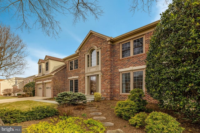 view of front of house with a garage, concrete driveway, and brick siding