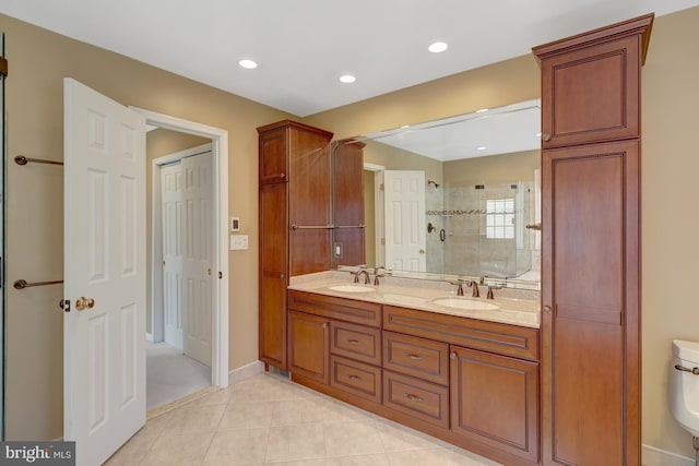 full bath with a stall shower, double vanity, a sink, and tile patterned floors