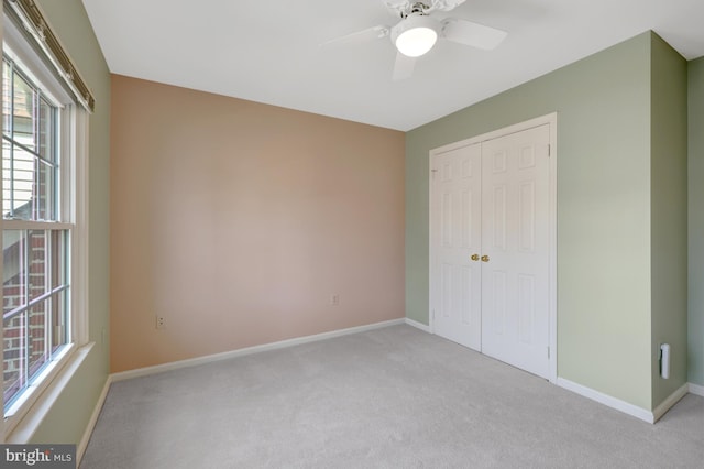 unfurnished bedroom featuring light colored carpet, a closet, multiple windows, and baseboards