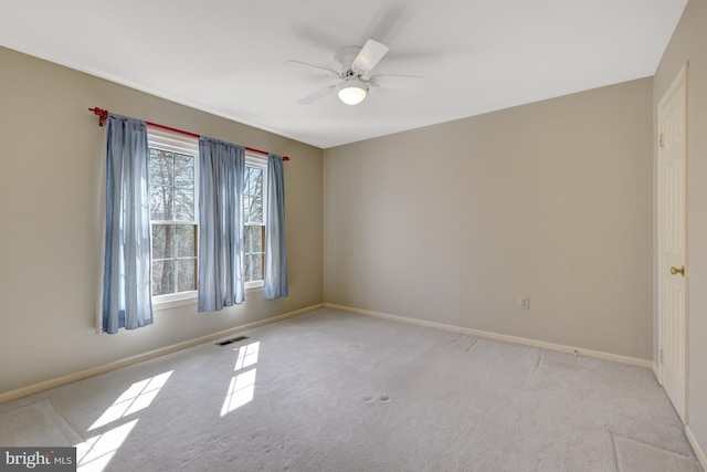 carpeted empty room featuring baseboards, visible vents, and a ceiling fan