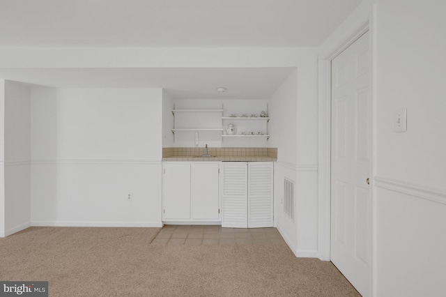 spare room with light carpet, a sink, visible vents, and baseboards