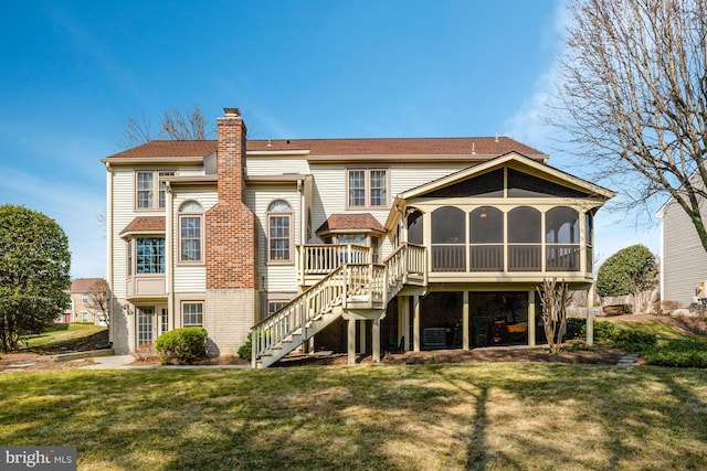 rear view of property featuring a yard, stairway, a chimney, and a sunroom