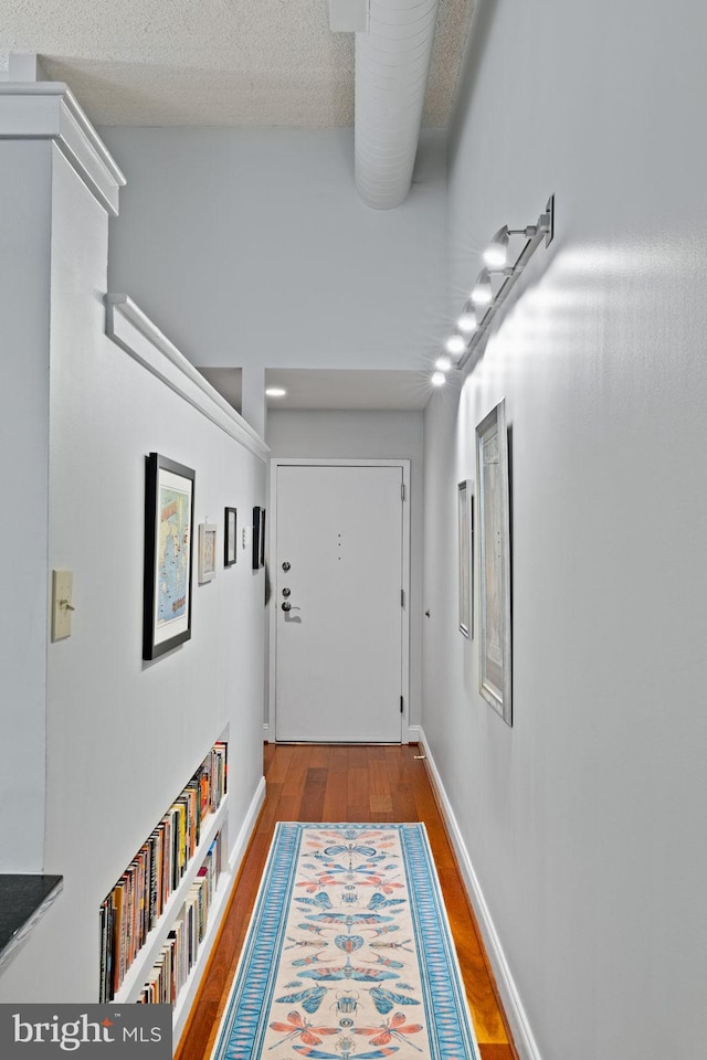 entryway featuring a textured ceiling, baseboards, and wood finished floors