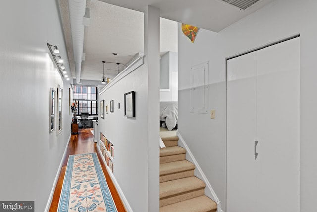 hall featuring visible vents, track lighting, wood finished floors, baseboards, and stairs