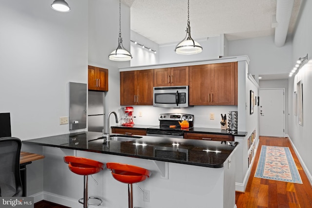 kitchen featuring a breakfast bar, stainless steel appliances, a sink, and wood finished floors