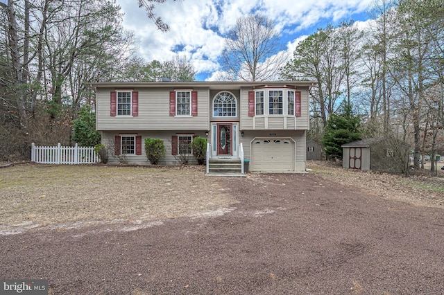 raised ranch featuring an outbuilding, a storage shed, a garage, fence, and dirt driveway