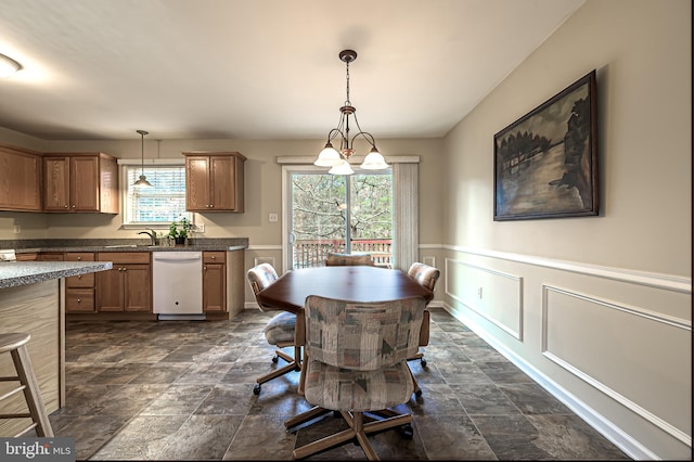 dining space with a wainscoted wall, plenty of natural light, a decorative wall, and stone finish flooring