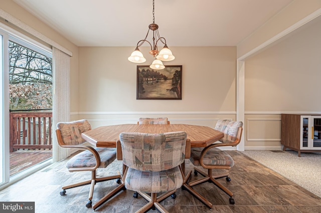 dining area featuring carpet floors, a wainscoted wall, breakfast area, a decorative wall, and an inviting chandelier