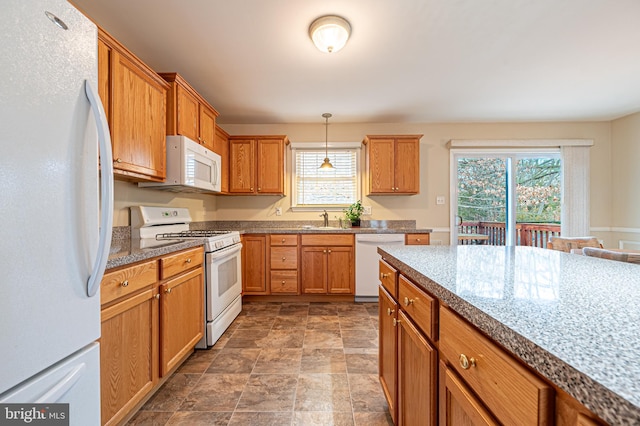 kitchen featuring white appliances, plenty of natural light, a sink, and decorative light fixtures