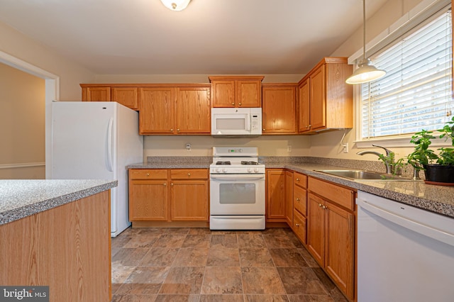 kitchen with white appliances, brown cabinets, decorative light fixtures, stone finish flooring, and a sink