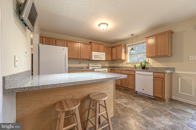 kitchen featuring decorative light fixtures, a sink, white appliances, a peninsula, and a kitchen bar