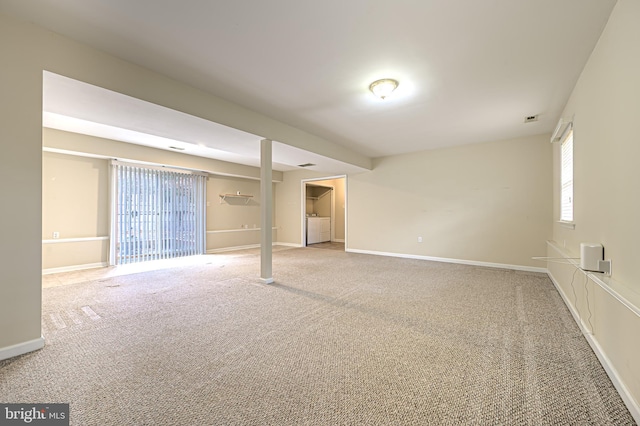 carpeted spare room with baseboards, visible vents, and washer and dryer