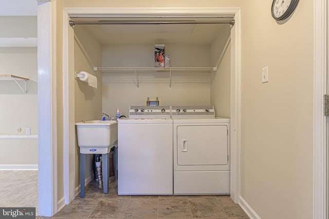 washroom with laundry area, a sink, washer and clothes dryer, and baseboards