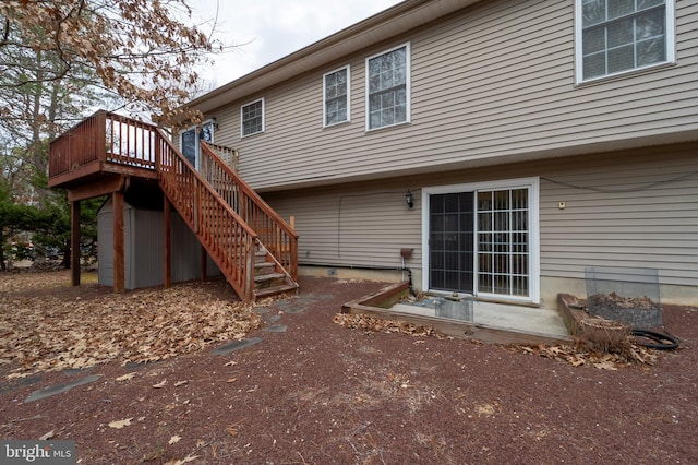 back of house featuring stairs and a wooden deck