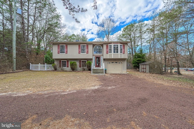 bi-level home featuring a garage, dirt driveway, a storage unit, fence, and an outdoor structure