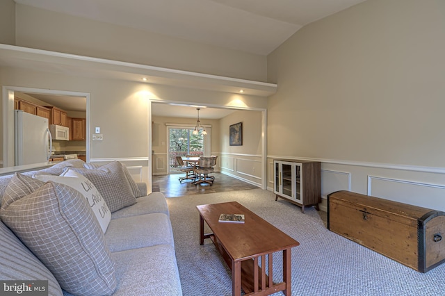 carpeted living room with a wainscoted wall, vaulted ceiling, and a decorative wall