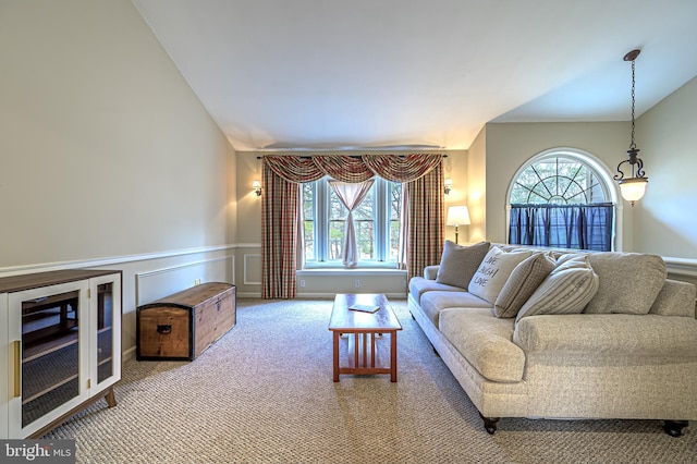 carpeted living room with lofted ceiling, wainscoting, plenty of natural light, and a decorative wall