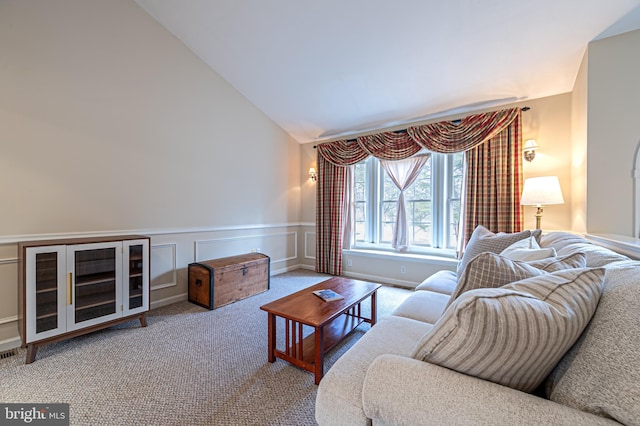 living room featuring carpet, visible vents, a decorative wall, wainscoting, and high vaulted ceiling