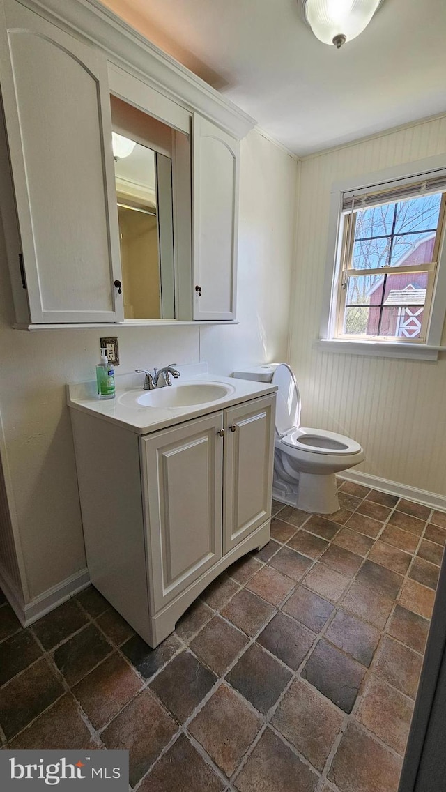 bathroom with baseboards, vanity, and toilet