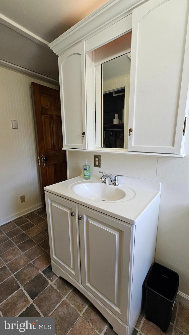 bathroom featuring stone tile flooring, vanity, and baseboards