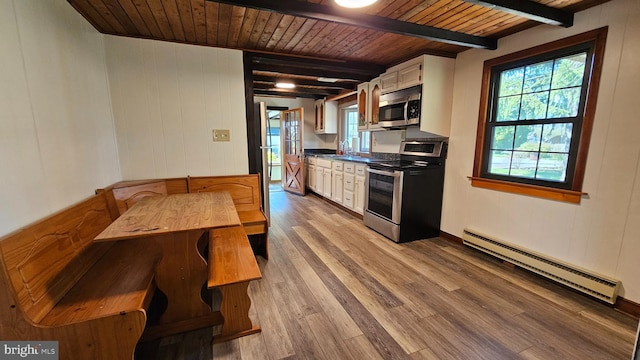 kitchen featuring wooden ceiling, a baseboard radiator, appliances with stainless steel finishes, beamed ceiling, and wood finished floors