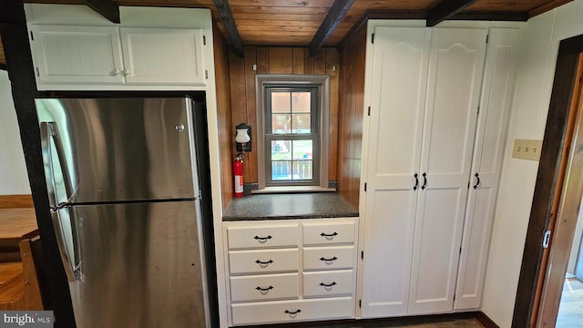 kitchen featuring beam ceiling, dark countertops, freestanding refrigerator, and white cabinetry