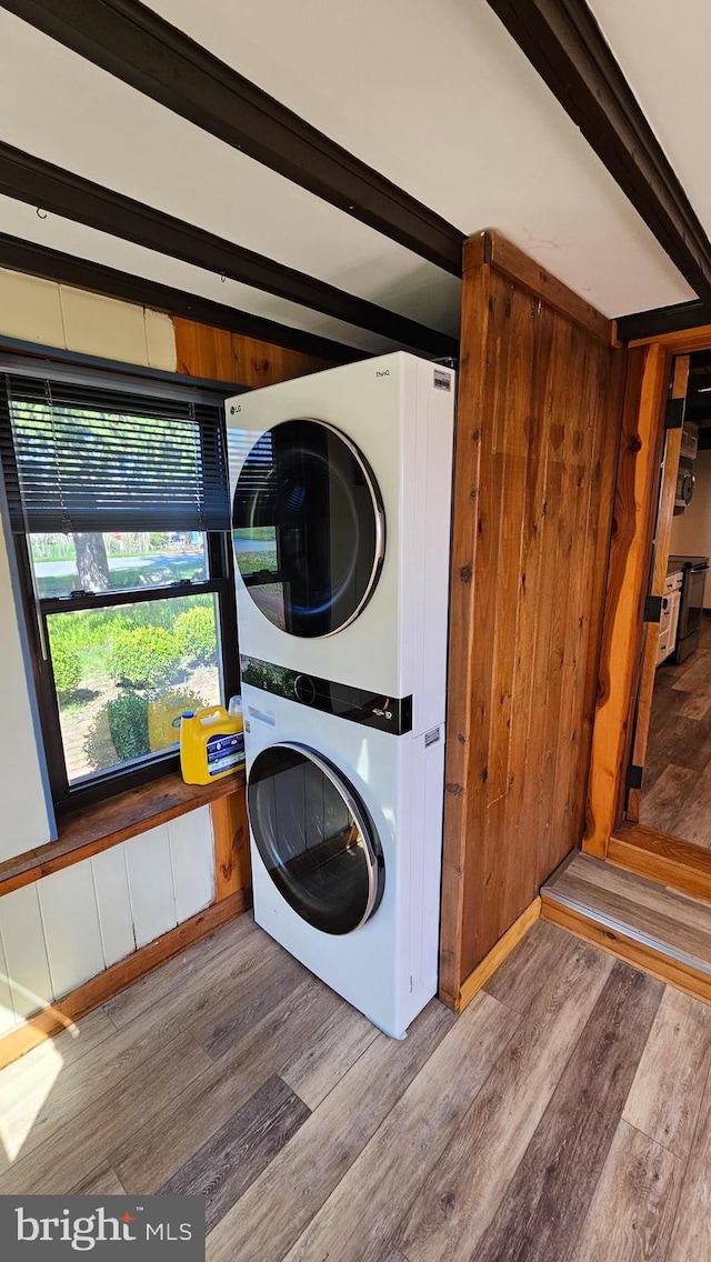 laundry room with laundry area, stacked washer / dryer, and wood finished floors