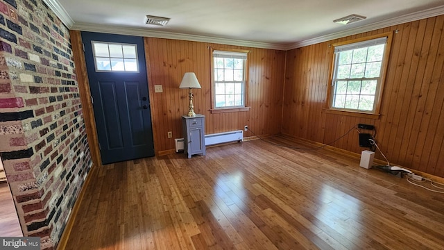 entryway featuring a baseboard radiator, brick wall, visible vents, hardwood / wood-style floors, and crown molding