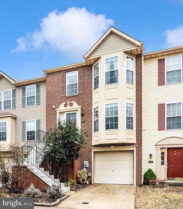 townhome / multi-family property featuring driveway, stairs, a garage, and brick siding