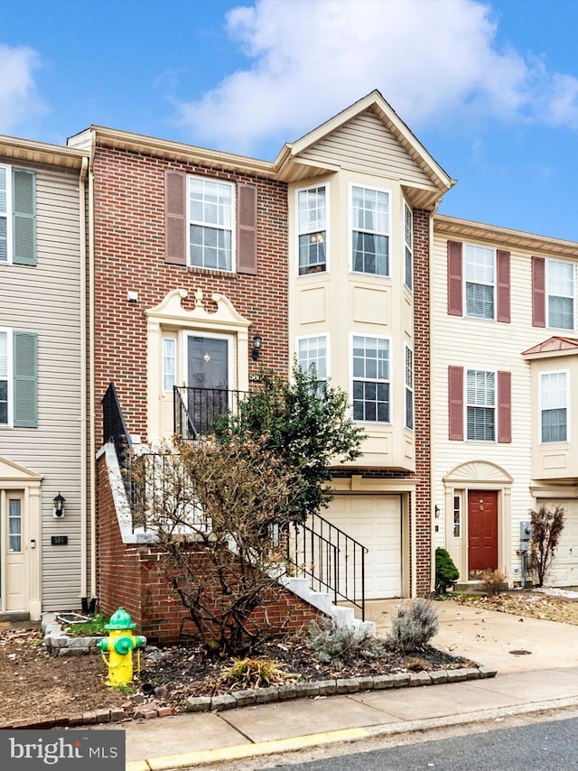 multi unit property featuring a garage, brick siding, and driveway