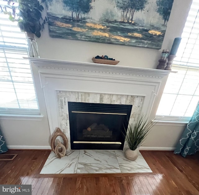 room details with a fireplace with flush hearth, visible vents, baseboards, and wood finished floors