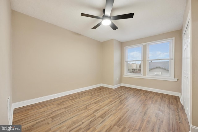 spare room featuring ceiling fan, light wood-type flooring, and baseboards